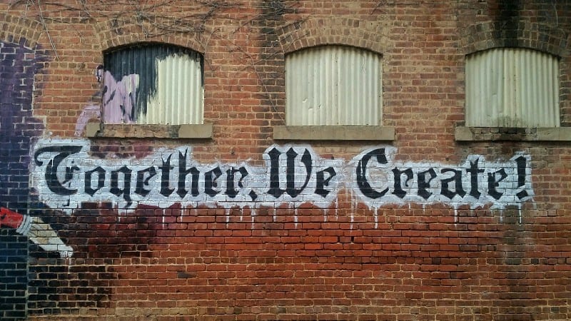 Collaborative Creativity in Action customer support and ux - collaboration
A mural on a brick wall that reads "Together, We Create!" with a person painting part of it.