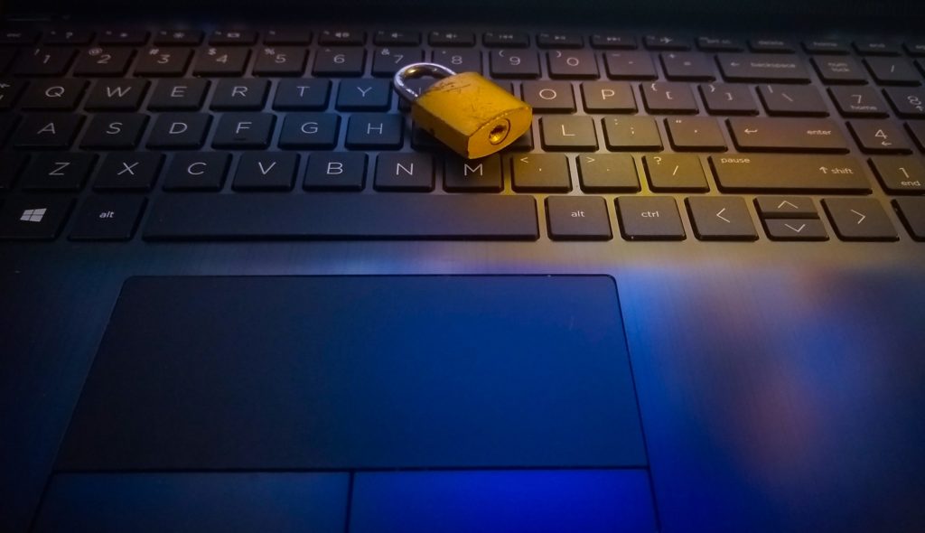 A gold-colored padlock resting on the keyboard of a laptop computer.