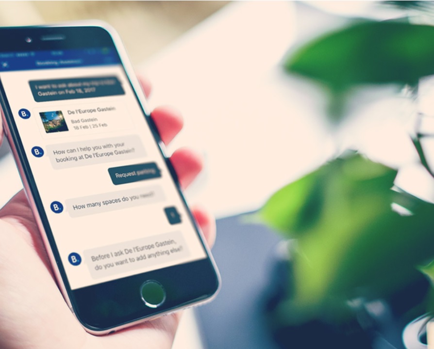 Chatbot Conversation About a Hotel Booking A person holding a smartphone with a chatbot conversation about a hotel booking.