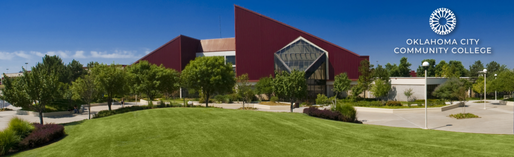 Exterior view of Oklahoma City Community College campus featuring a modern building with distinctive red metal siding and large glass entrance. The building is surrounded by well-maintained landscaping including a large green lawn in the foreground, mature trees, and planted areas with walking paths. The OCCC logo appears in the upper right corner of the image against a clear blue sky.
